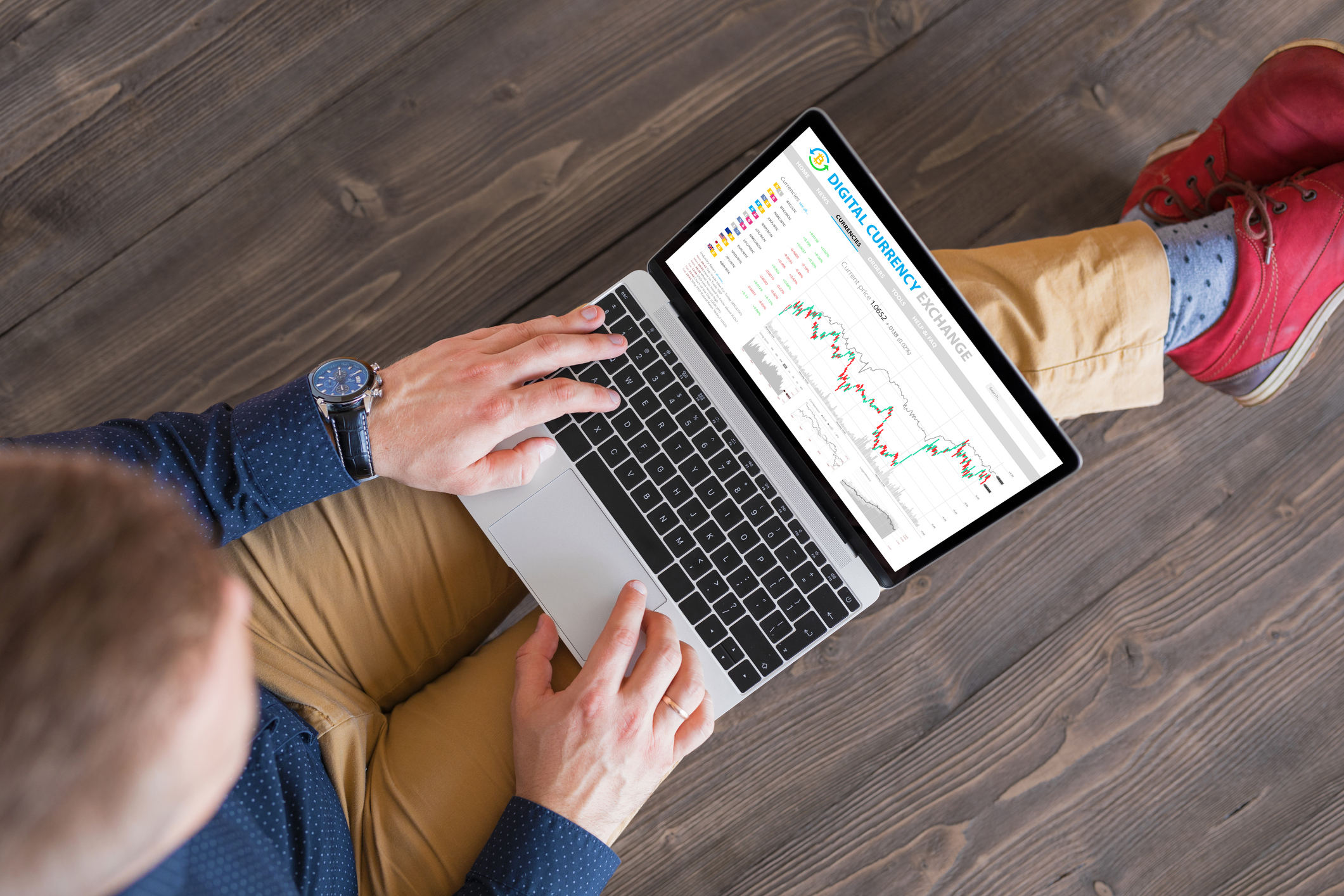 Person sitting with computer with stock chart on it.