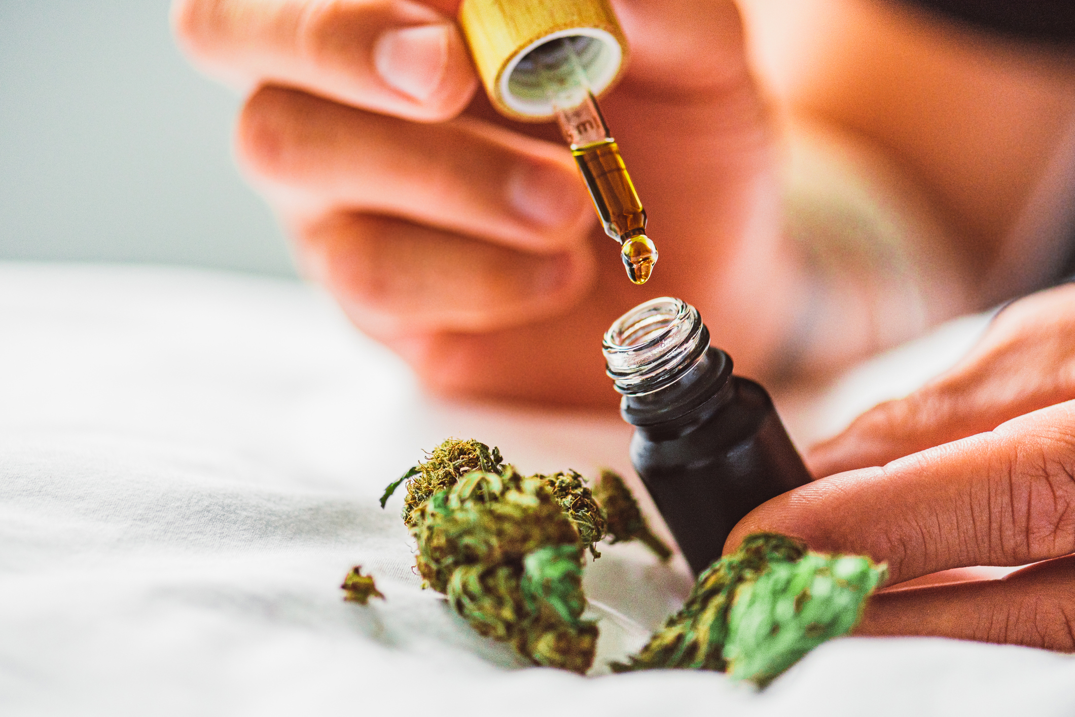 Pair of hands using a CBD dropper
