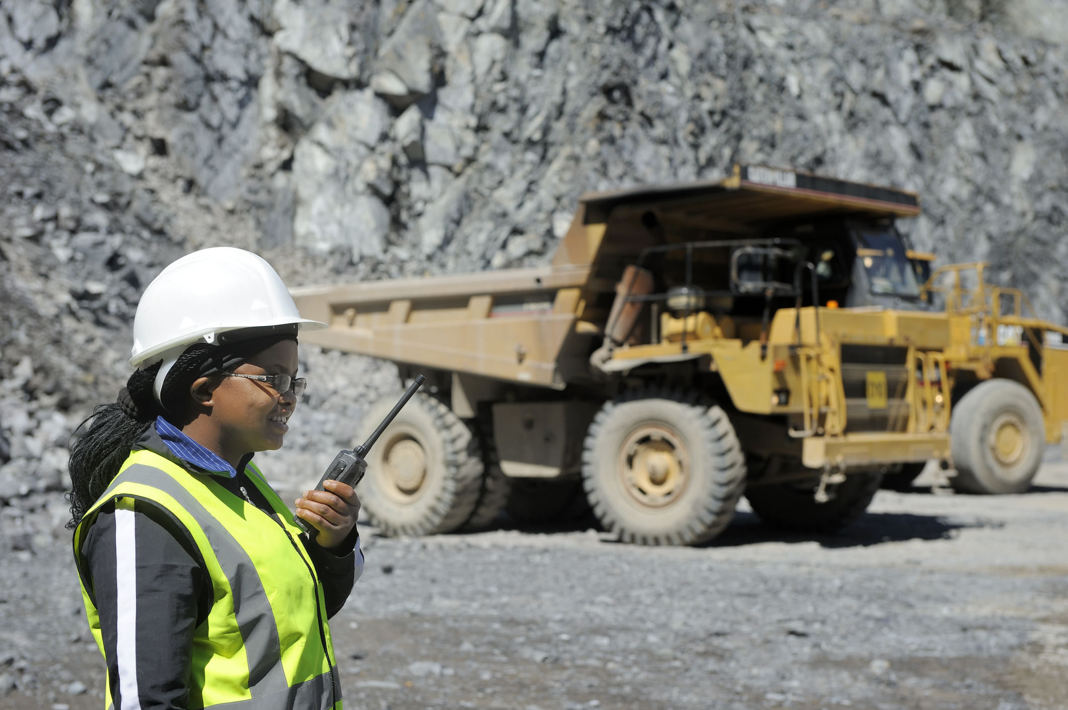 21_05_18 A person in protective gear talking on a communications device with a dump truck in the background _GettyImages-155380861