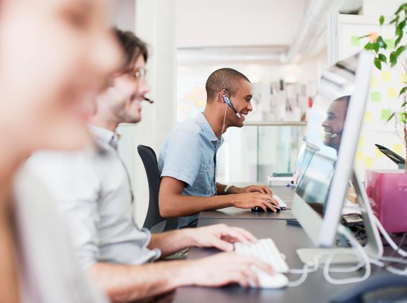 Three people wearing headsets in a call center.