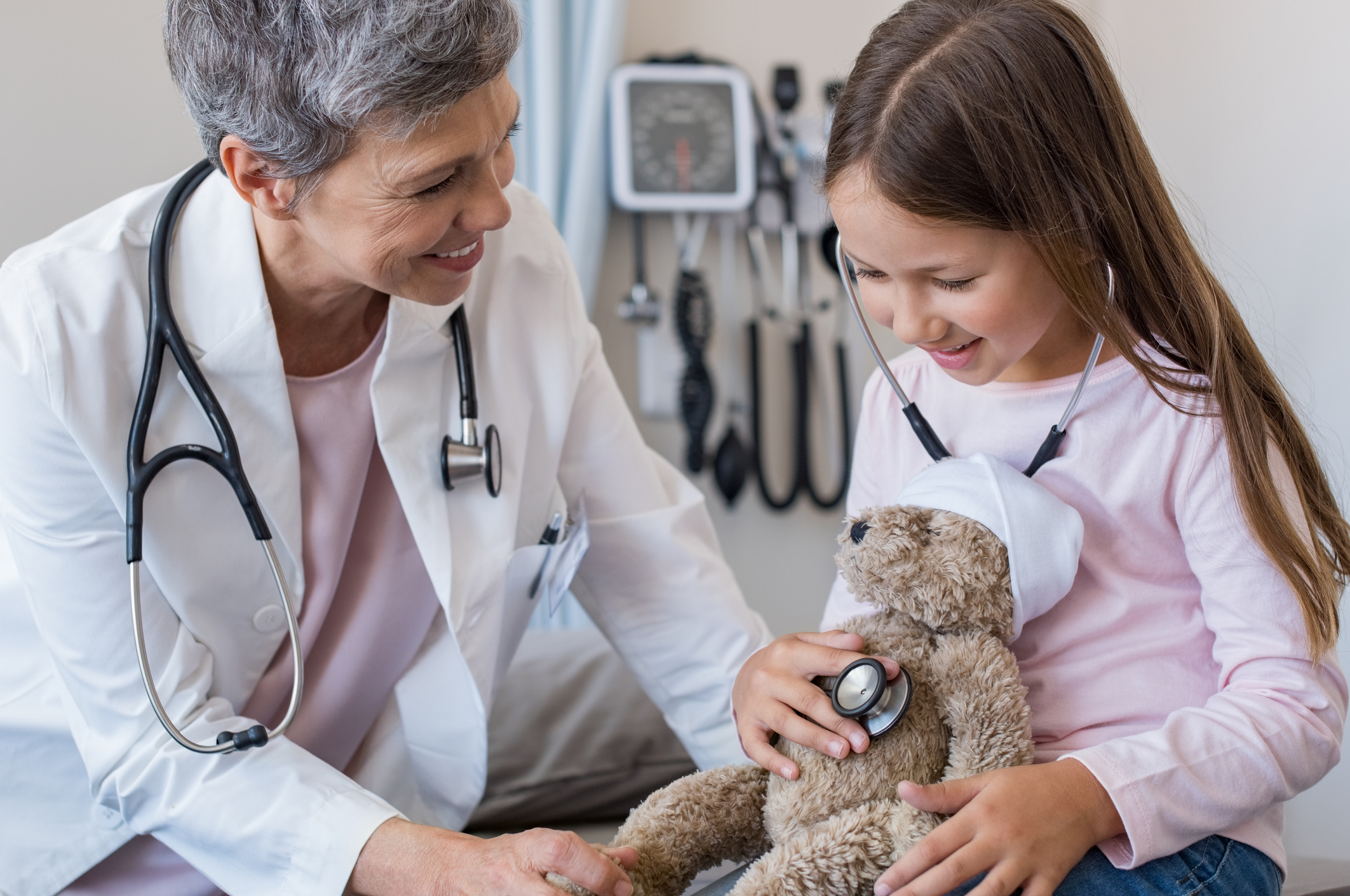 Child with doctor listening to heartbeat of stuffed bear.