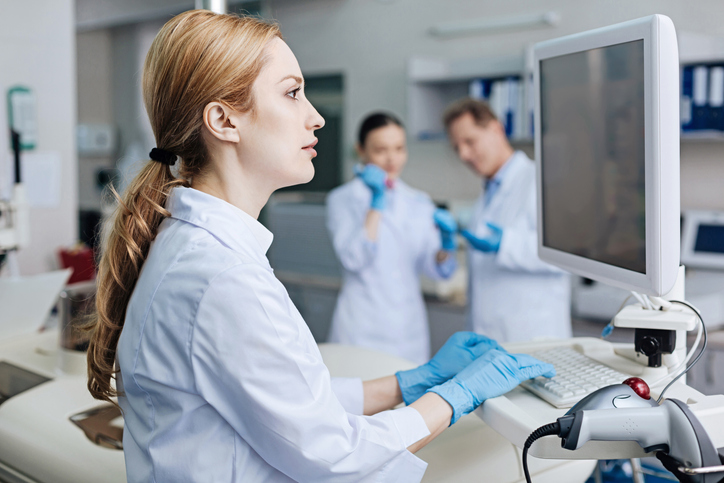 A lab technician looks at results on a computer.