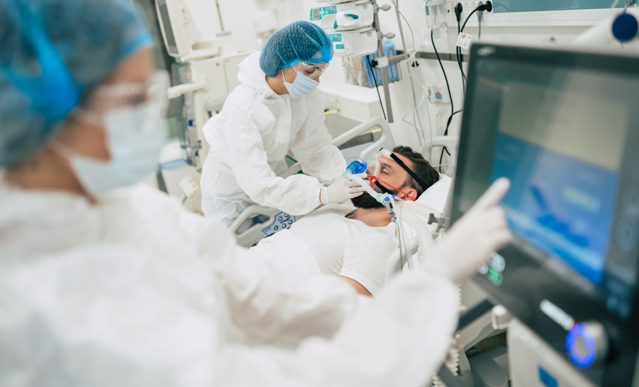 Patient on respirator, with medical professionals working.