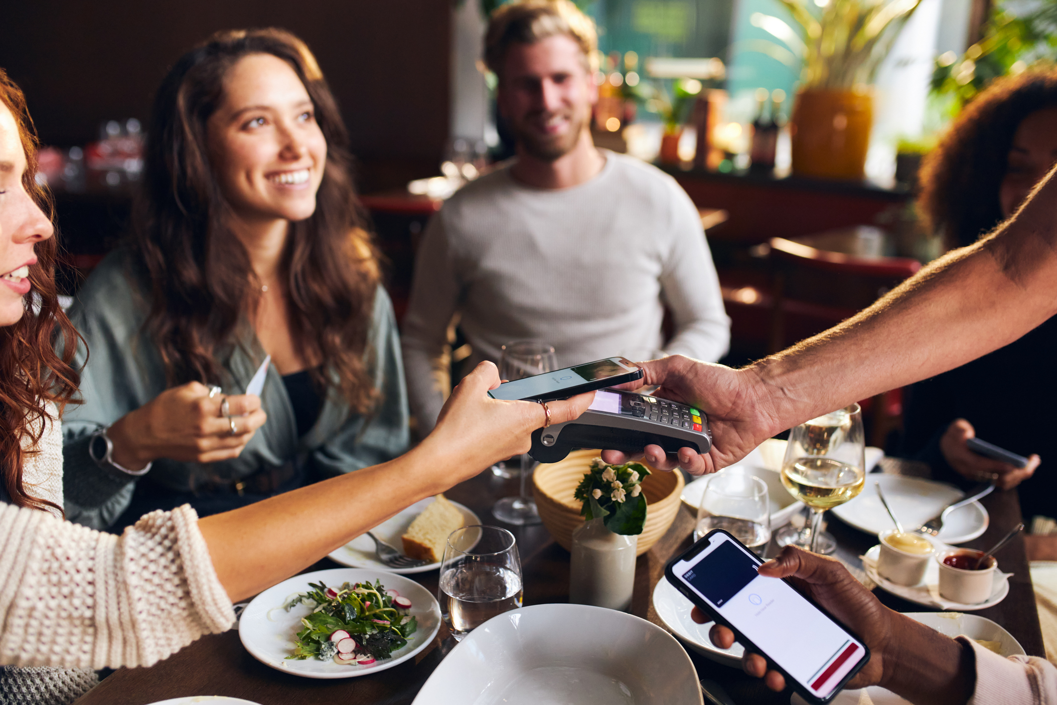People make payments with their phones at a restaurant.