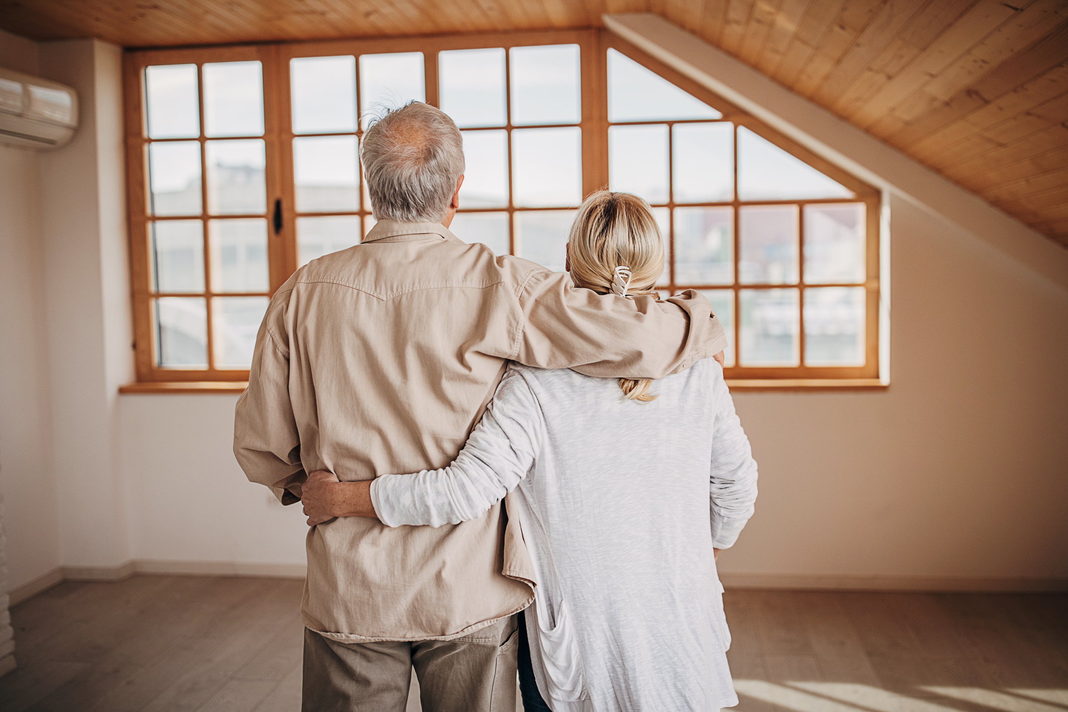 Two people looking out a window in an empty loft-looking room.