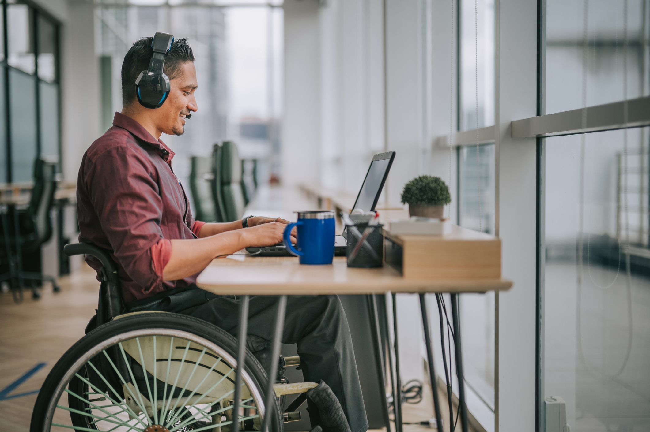 Man in wheelchair sitting at desk on computer.