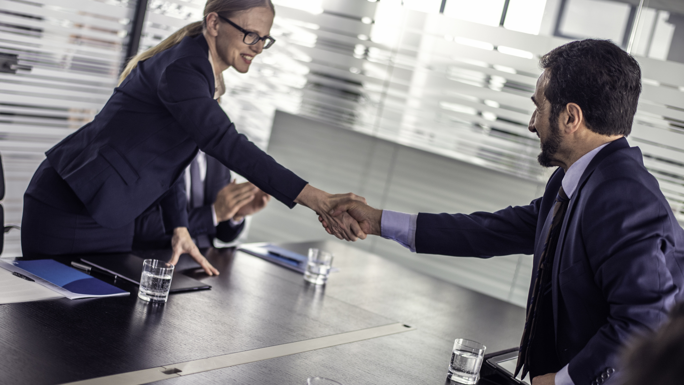 People are shaking hands in a conference room. 