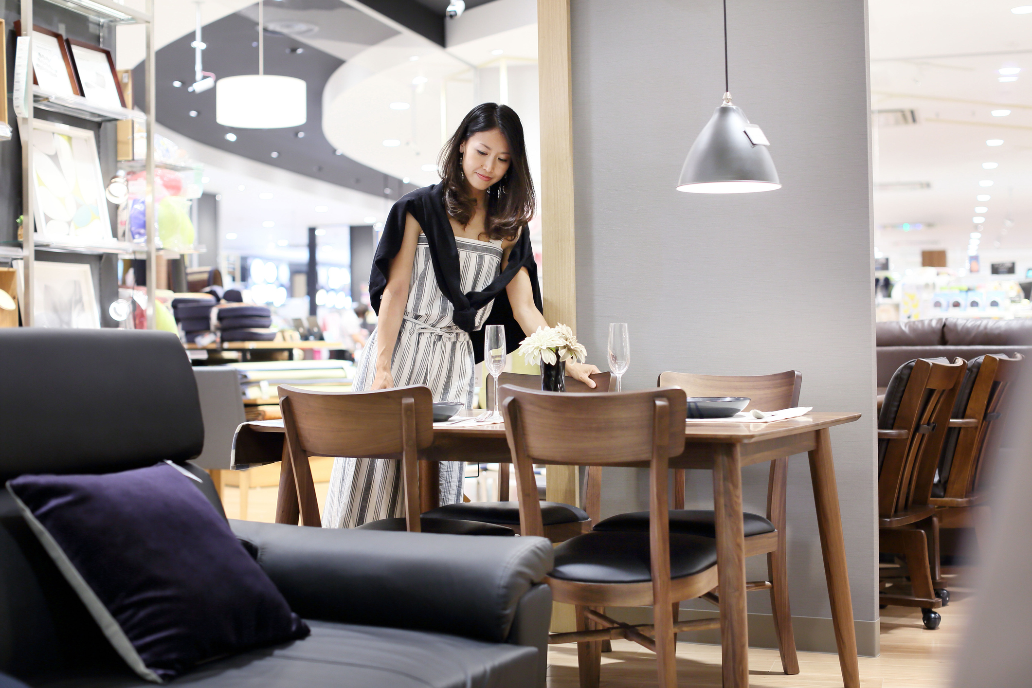 A person pulling a chair out from a table in a furniture showroom