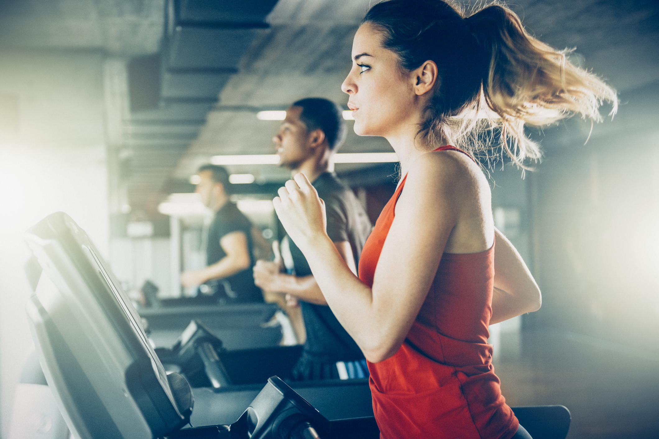 People are running on treadmills in a gym.