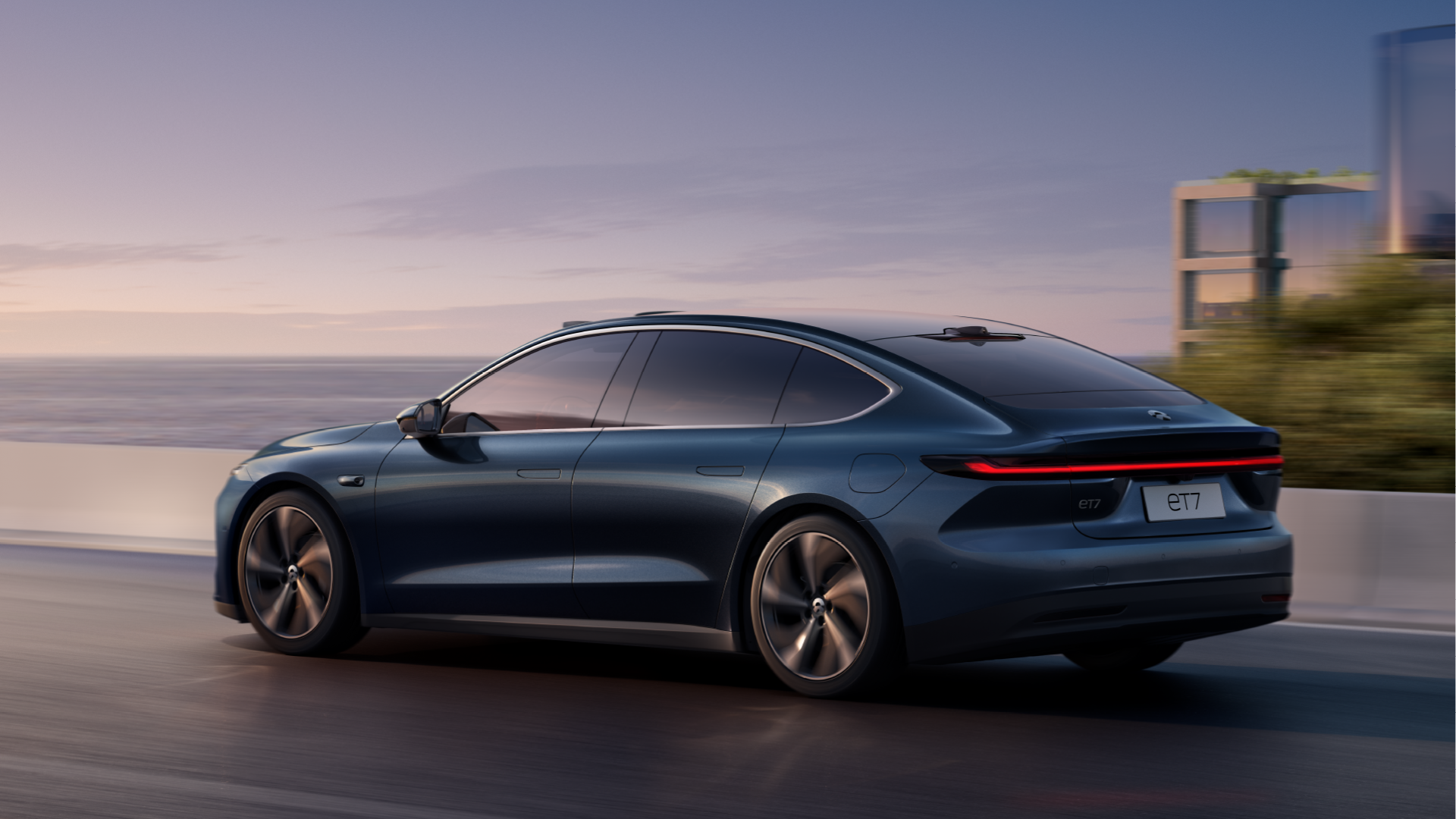 Blue ET7 Nio sedan on waterfront highway.