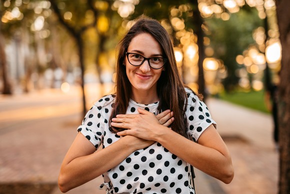 Someone has their hands over their heart, smiling. 