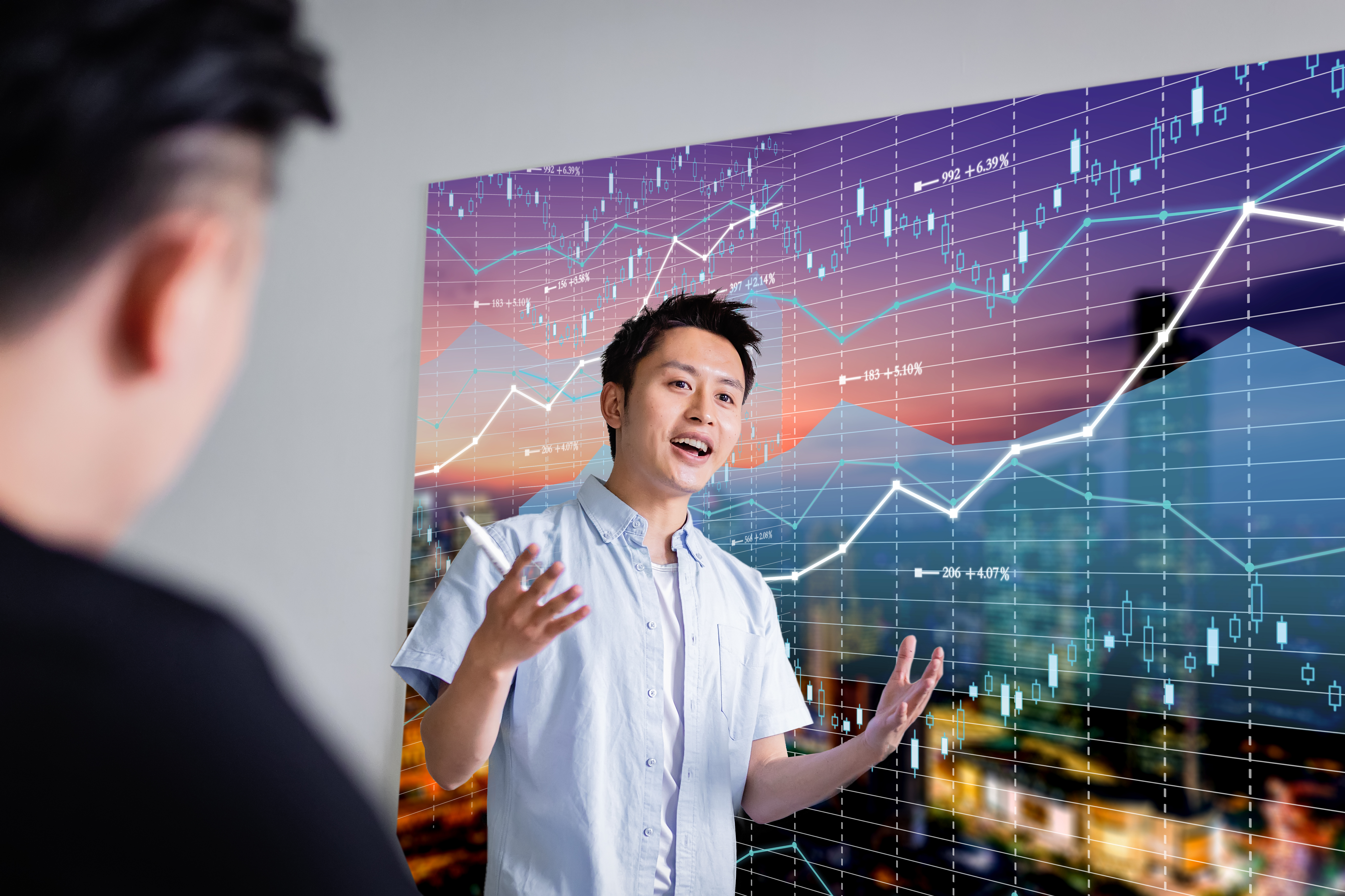 Person lecturing in front of stock chart going up.