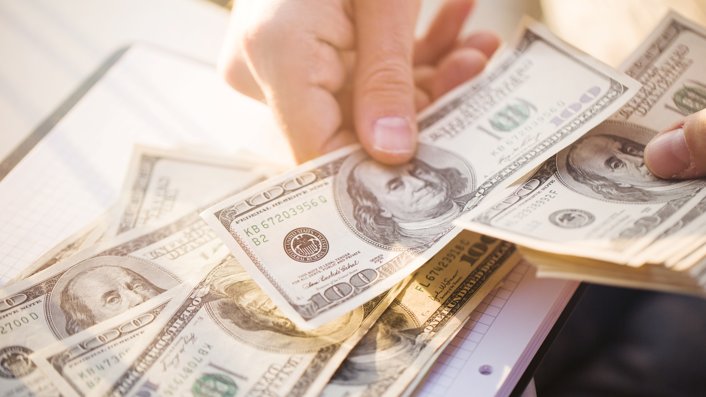 A hand counting $100 bills.