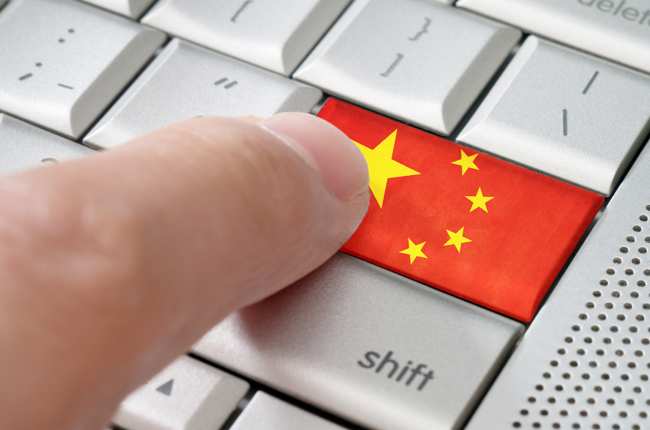 Finger pressing Chinese flag key on computer keyboard.