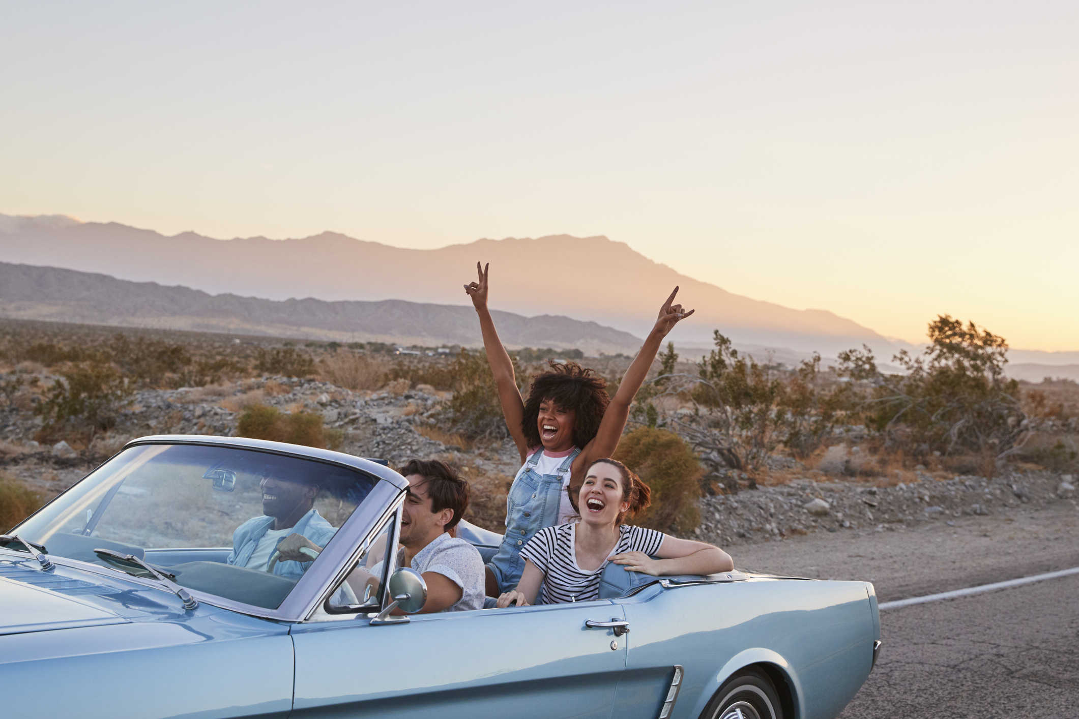 A group of friends on a road trip in a blue convertible.