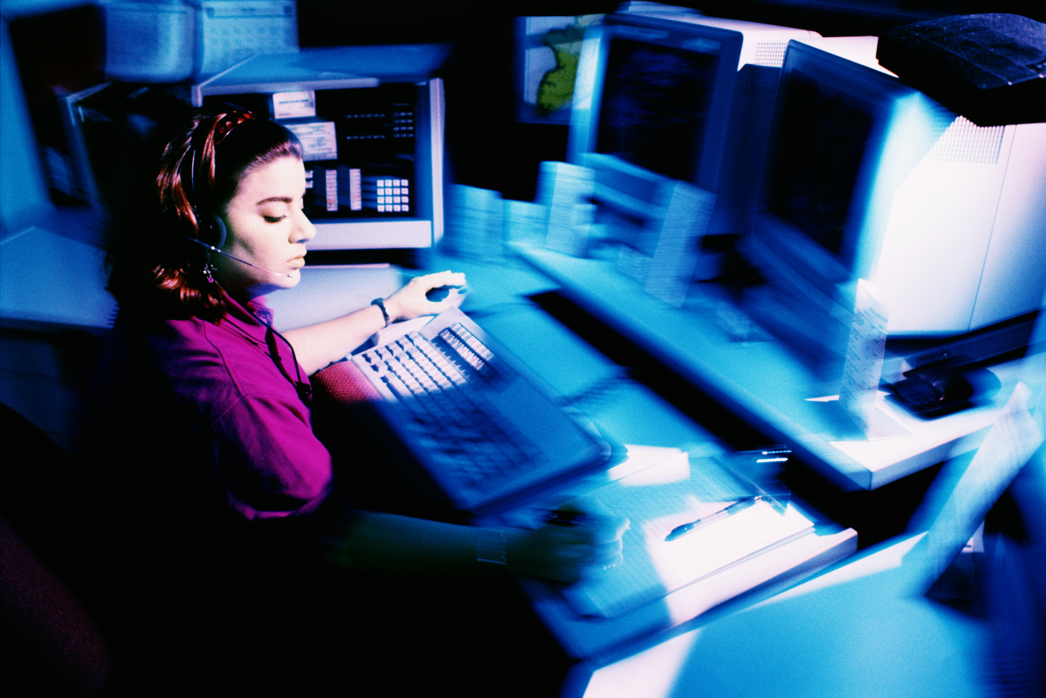 Woman sitting amongst computers screens.