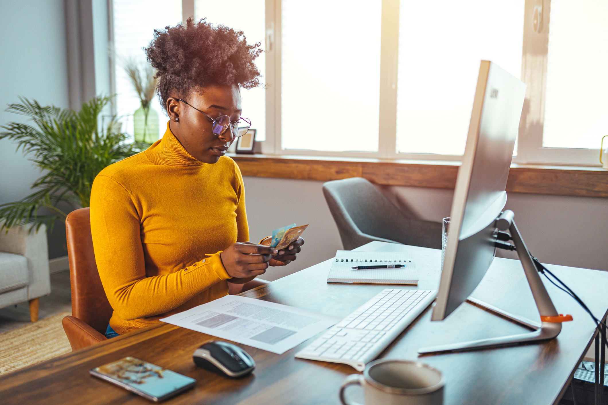 Person looking at documents and using computer while sitting at desk in office.