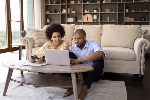 A couple of investors at home looking for stocks to buy together.