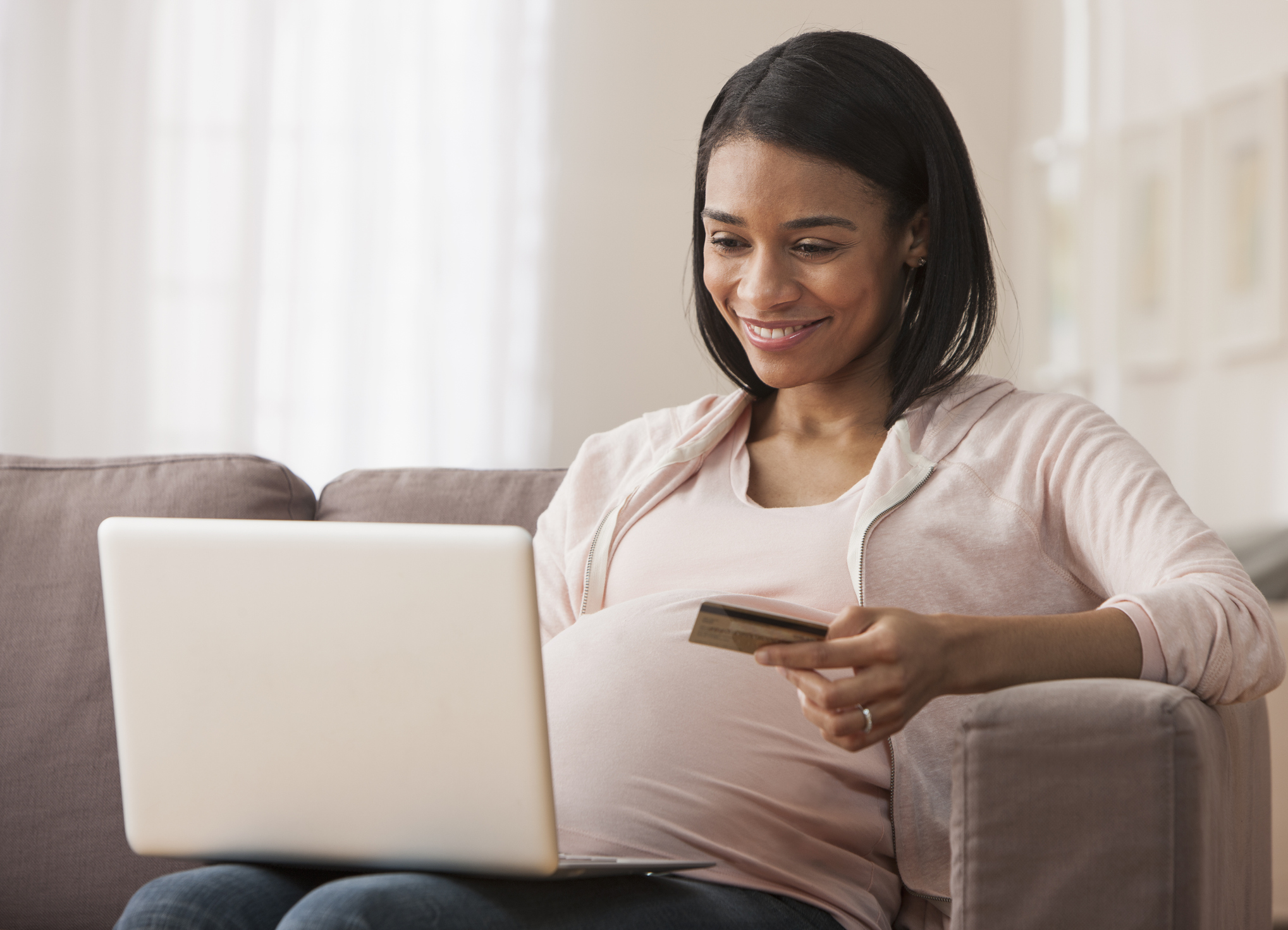 A person with a credit card in one hand and the other hand on a laptop keyboard.