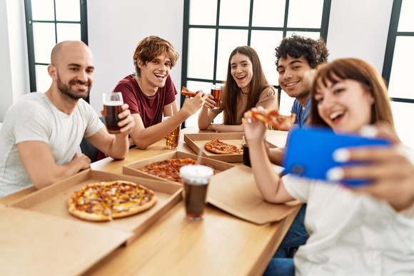 A group of people drinking cola and eating pizza.