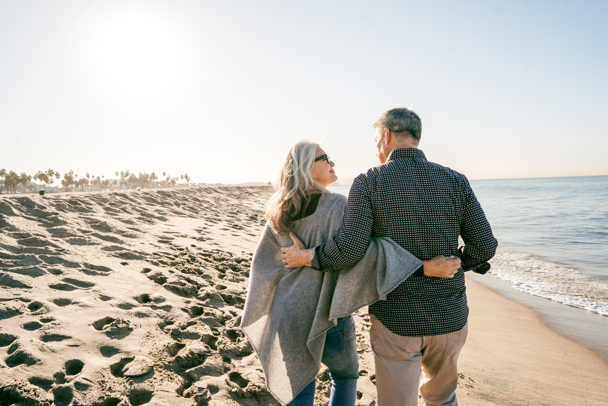 Older couple walking on a sunny beach.