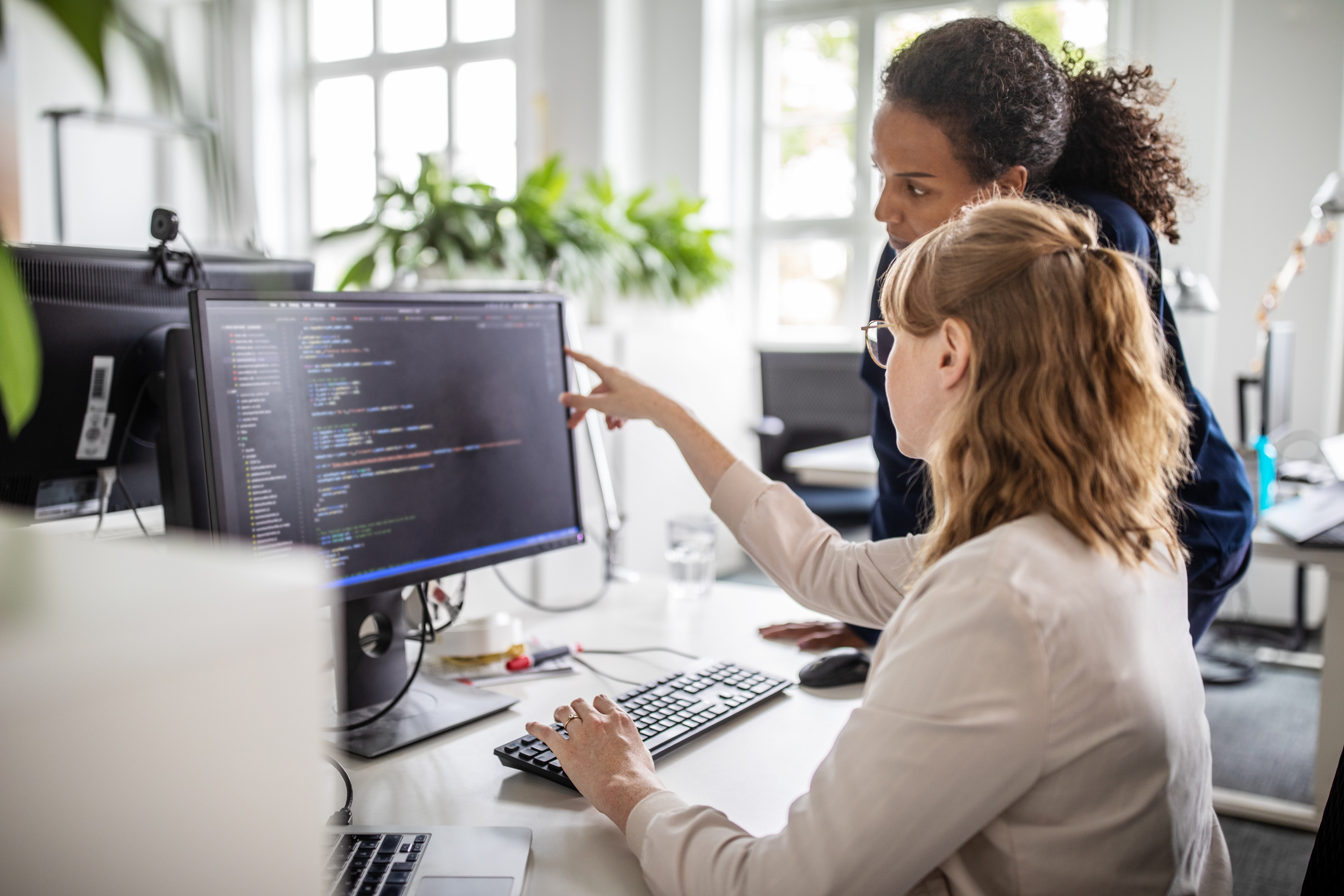 Two people working at a computer showing work on a monitor.
