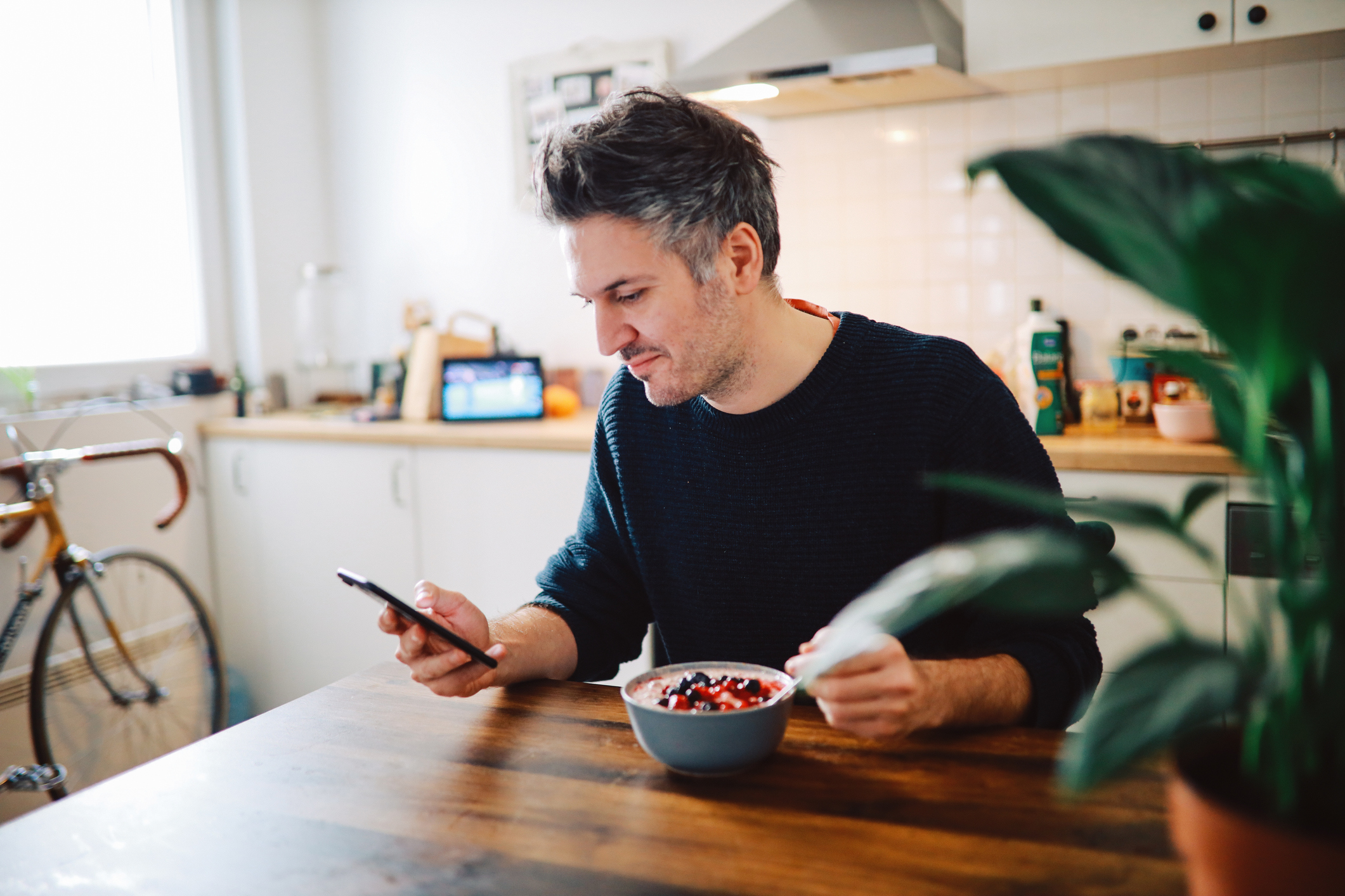 A person using a smartphone while sitting at the kitchen table.