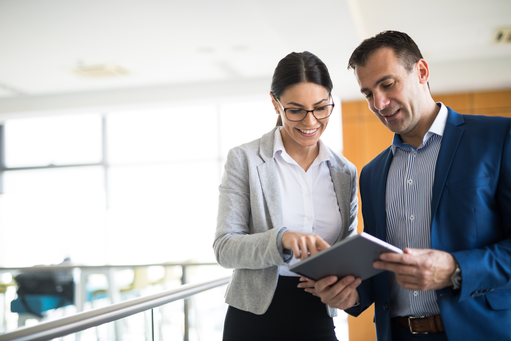 Two people smiling while looking at tablet.