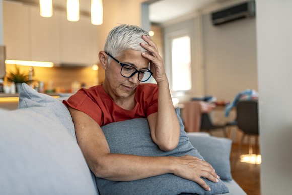 A person on a couch holding their head.