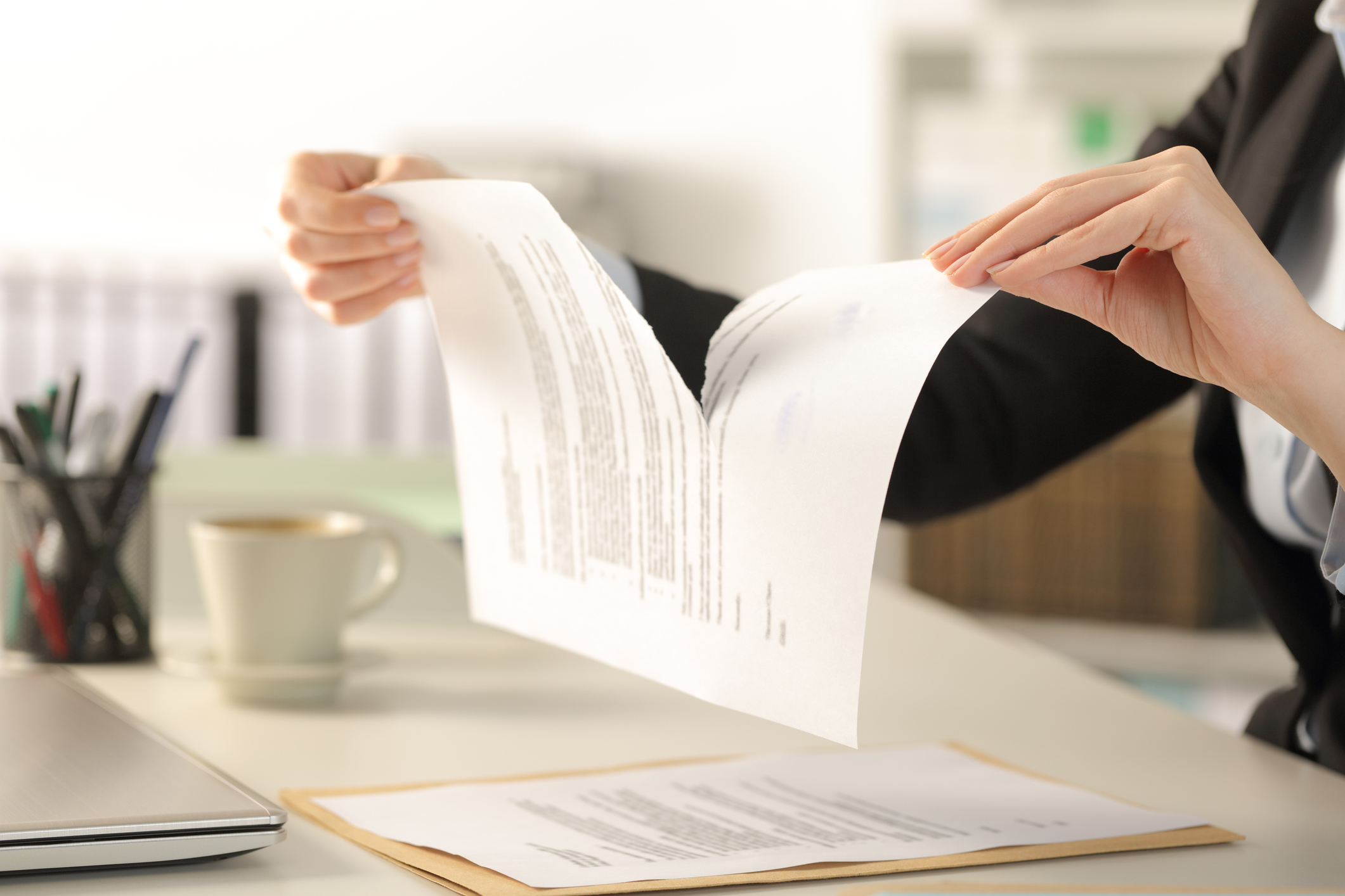 A businessperson tearing a document in an office.