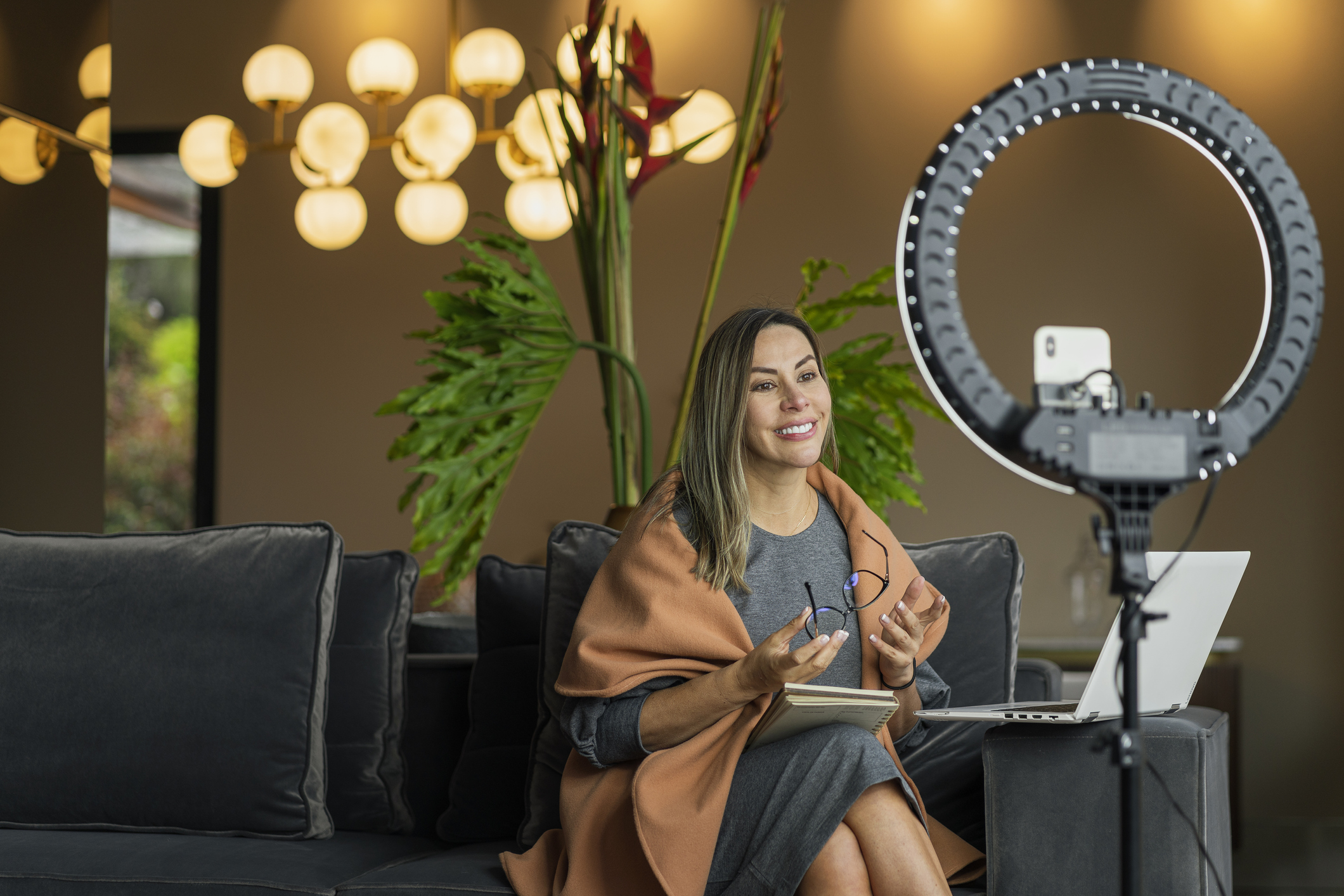 A person records a video using a smartphone and a ring light.