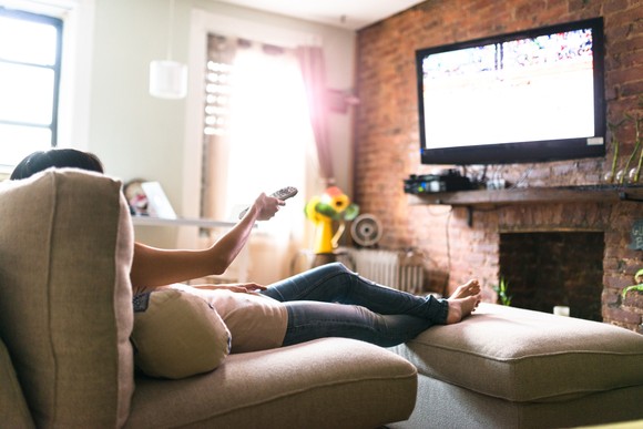 A person watching television while sitting on a couch.