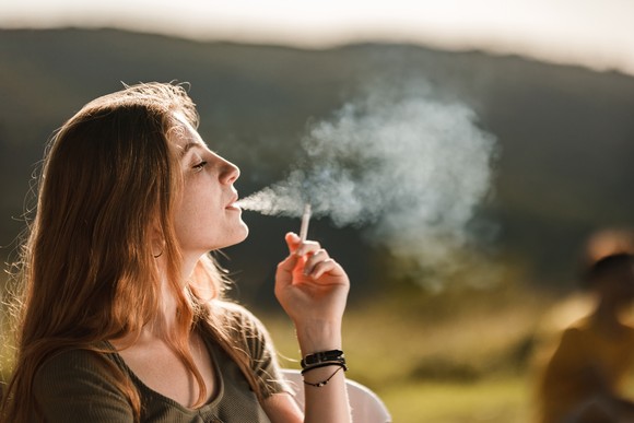 A person smokes a cigarette while outside.