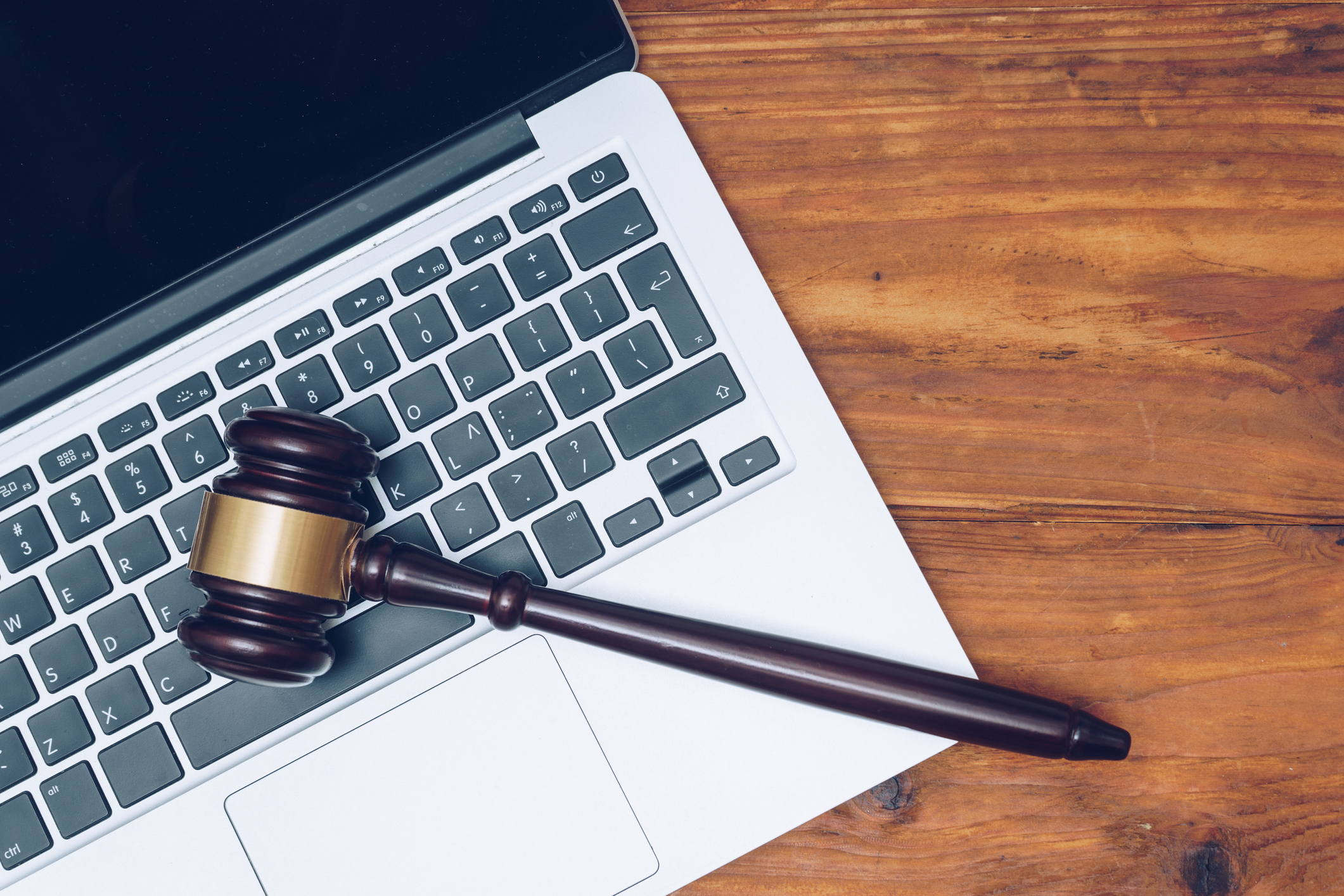 A gavel laying on top of an open laptop on a desk.
