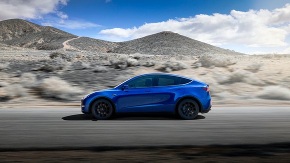 A blue car on a desert road.