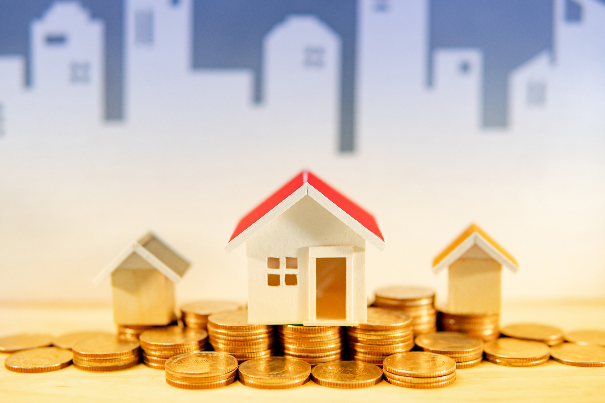 Little houses sitting on piples of coins.