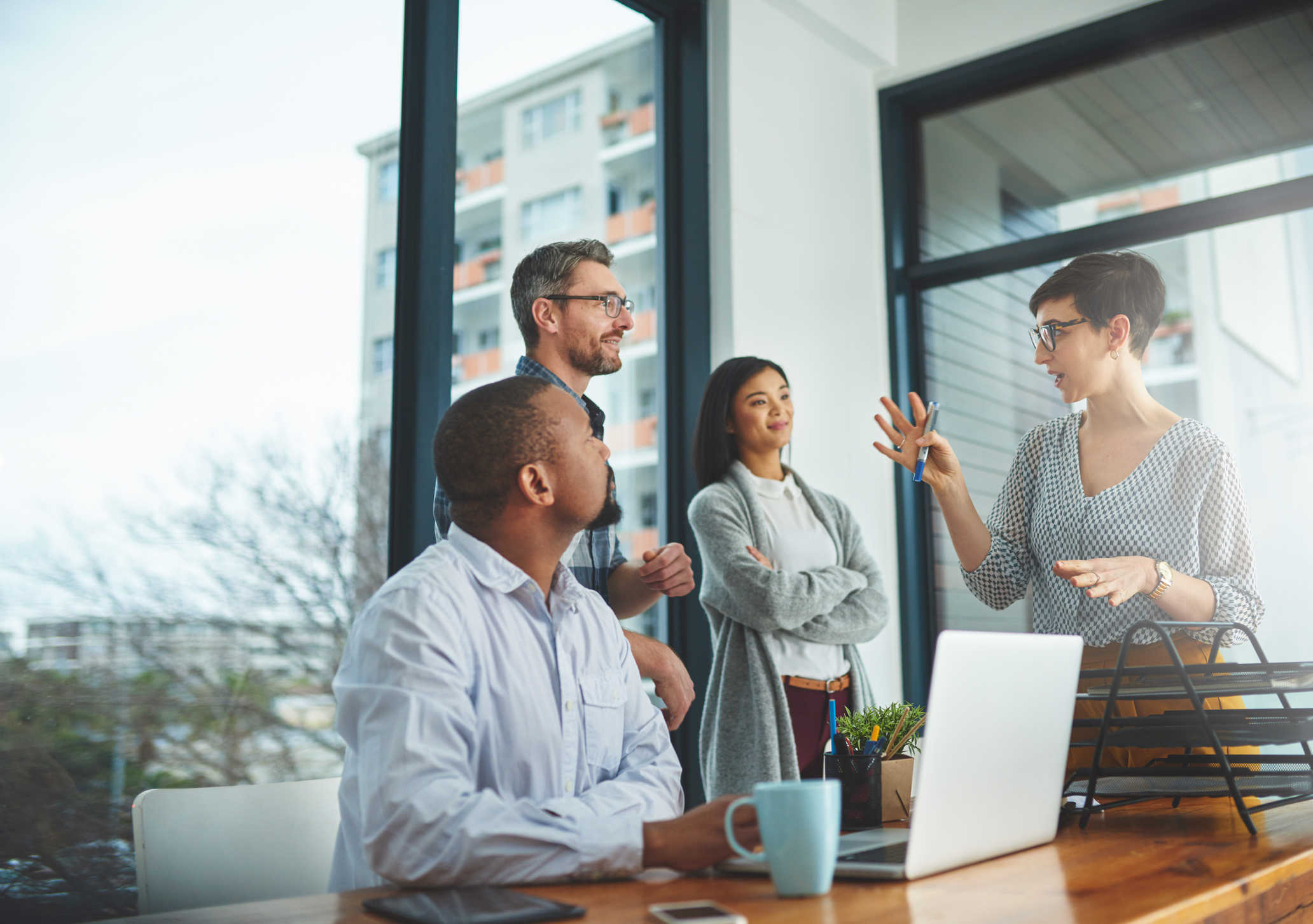 A group of four speaks in an office.