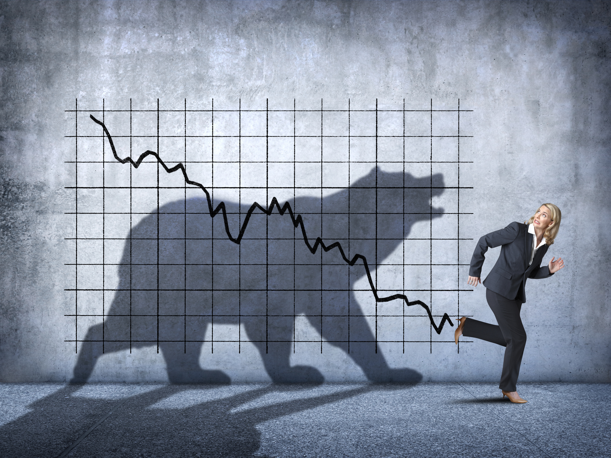 Silhouette of a bear behind a downward-trending stock chart and a person running away.