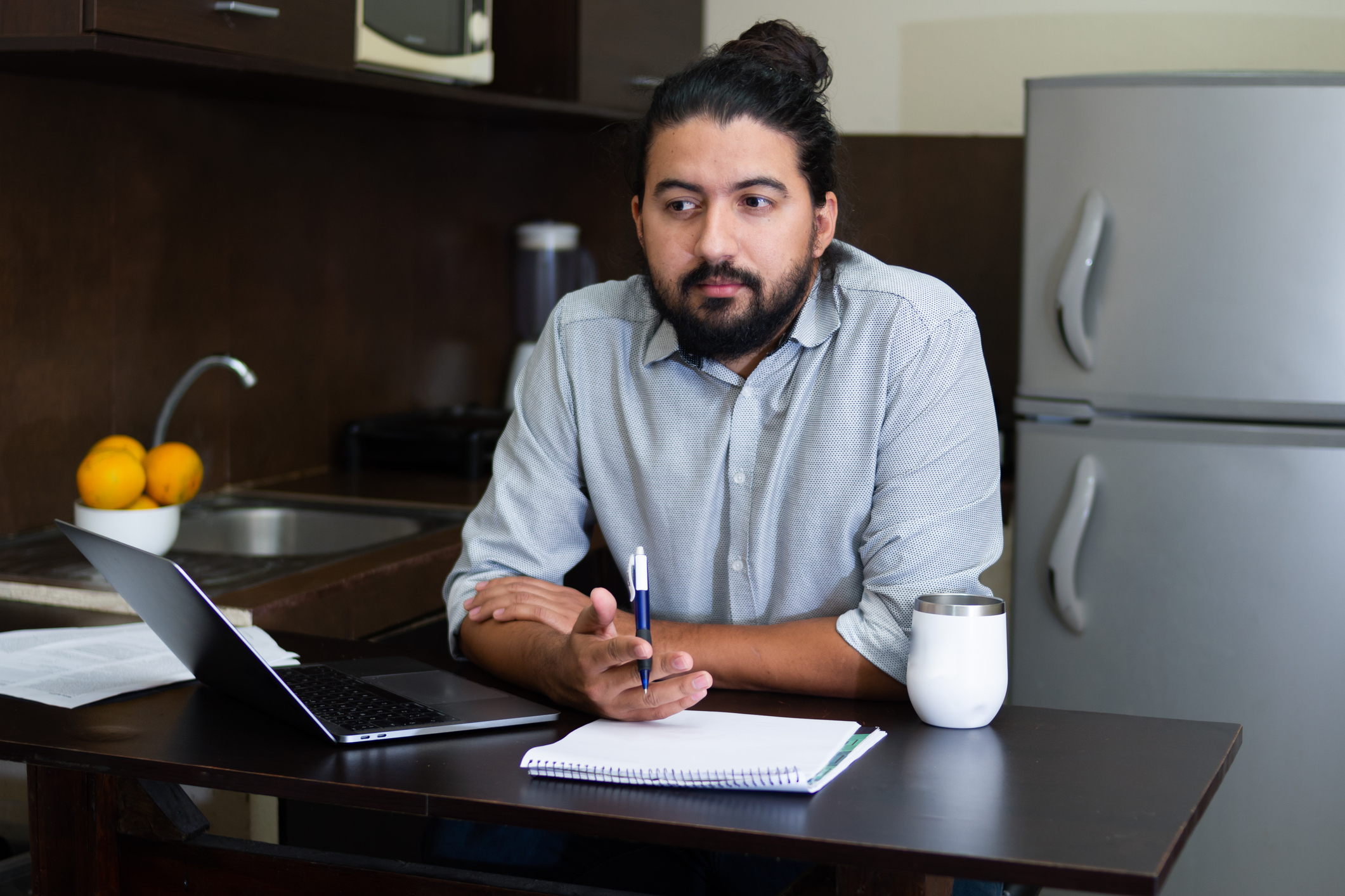 A person looking at a laptop in a kitchen.