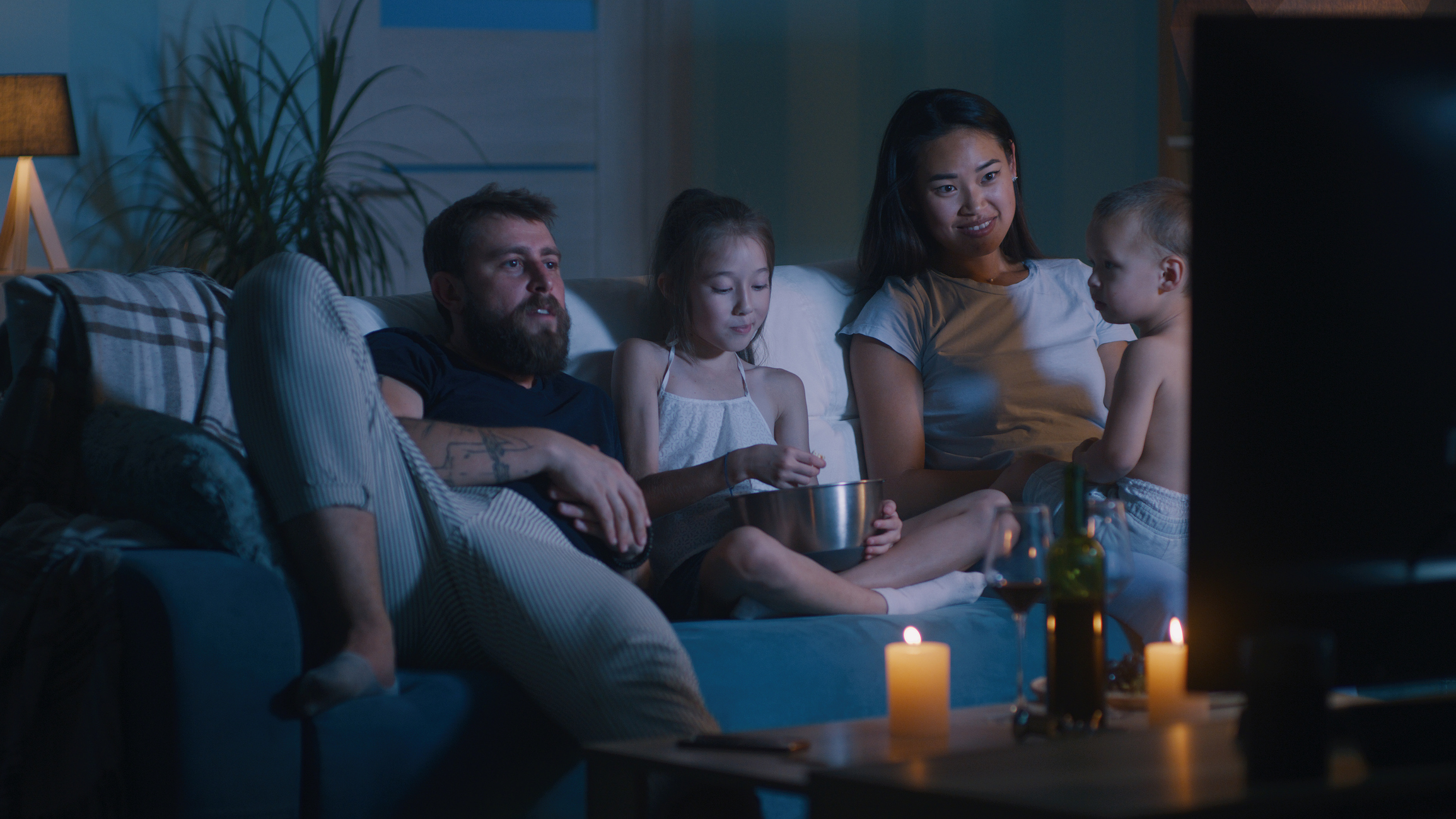 Family sitting on the couch watching television.