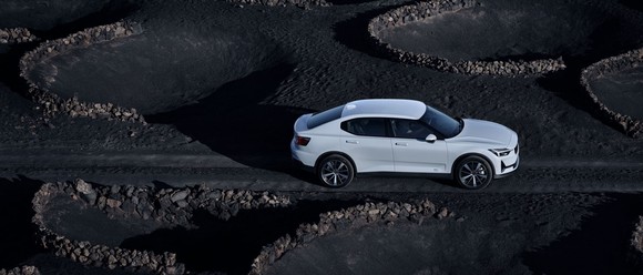 A white Polestar 2 on a dark road setting.