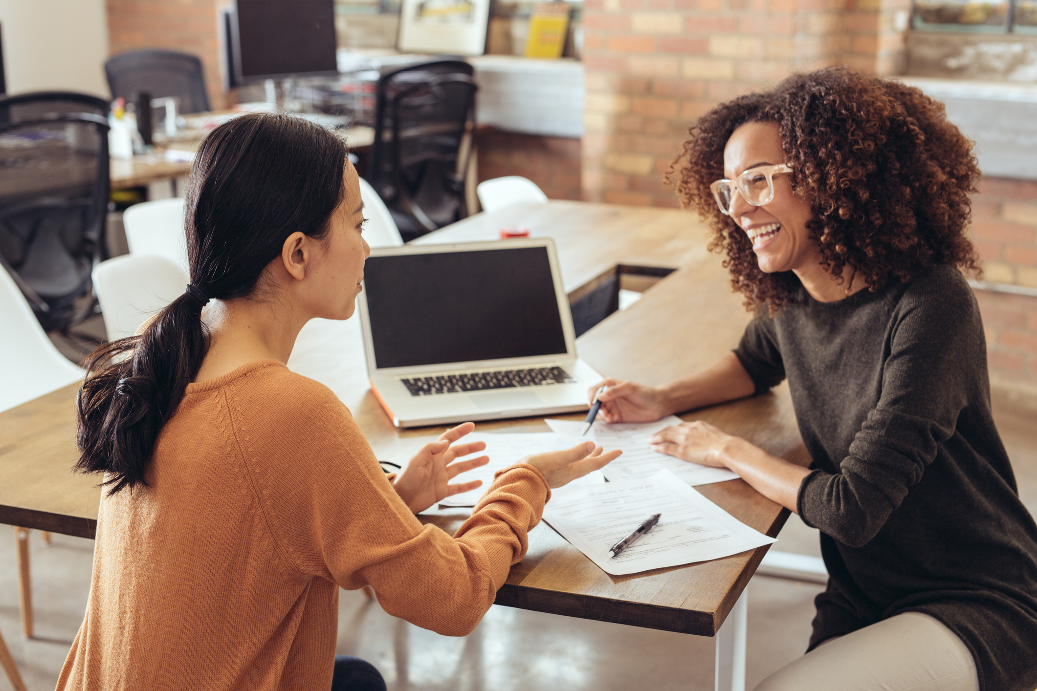 People have a conversation in an open office setting.