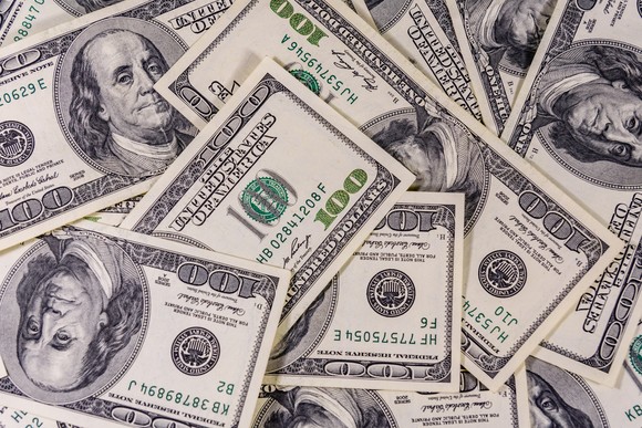 Many one-hundred dollar bills spread out on a surface.