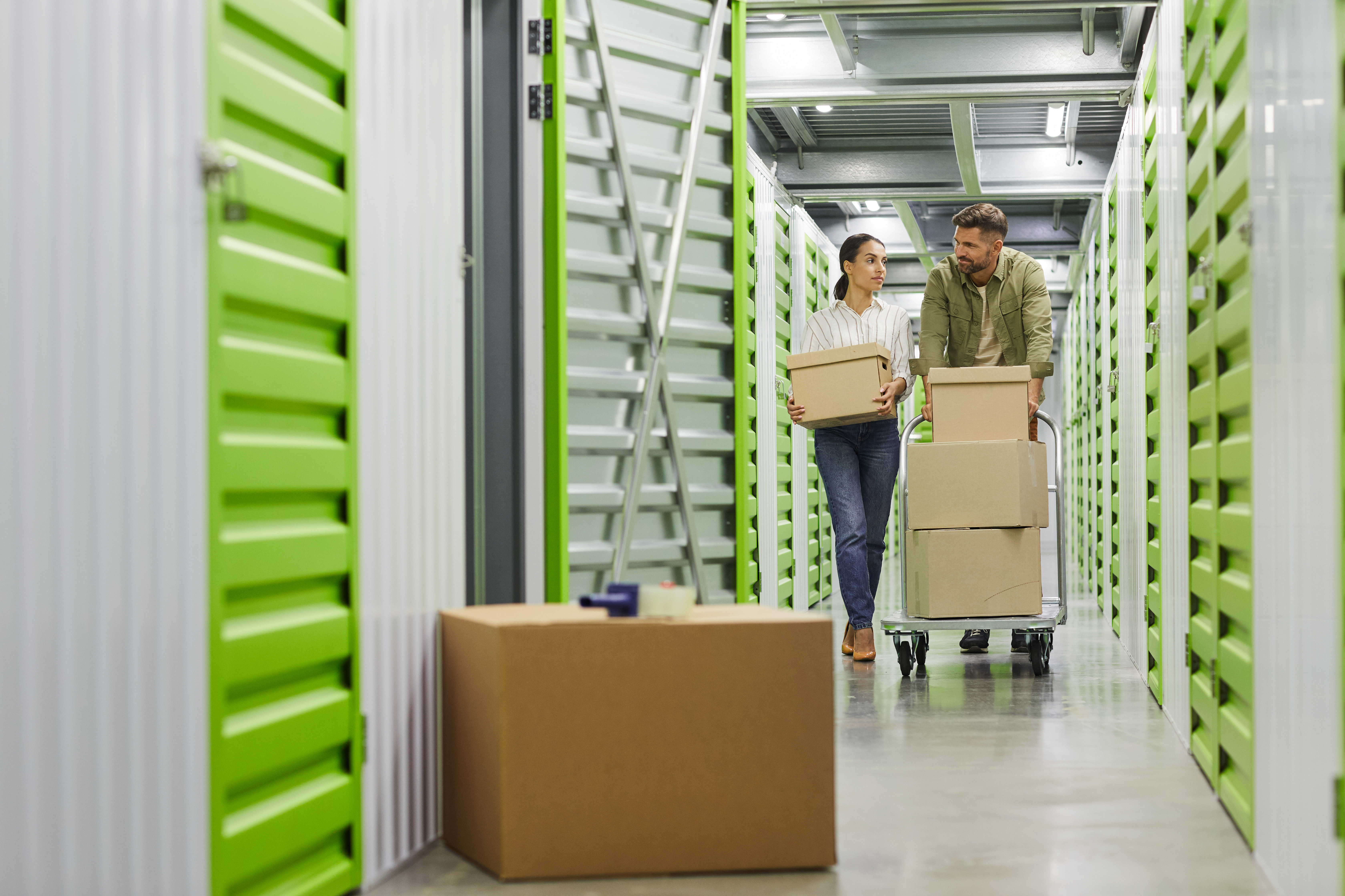 Two people moving items into a self-storage unit.