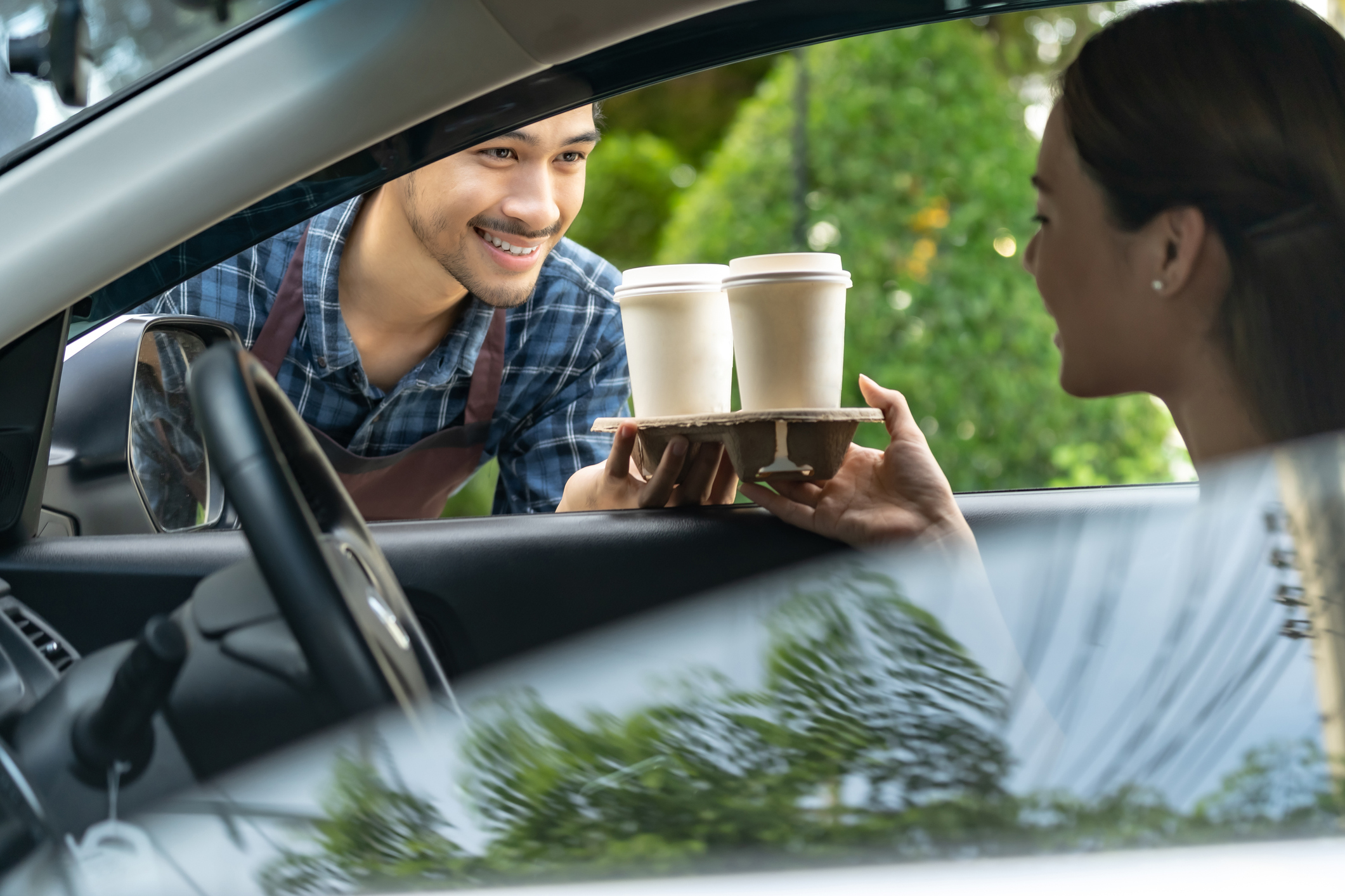 Barista at drive through coffee location serving customer in car