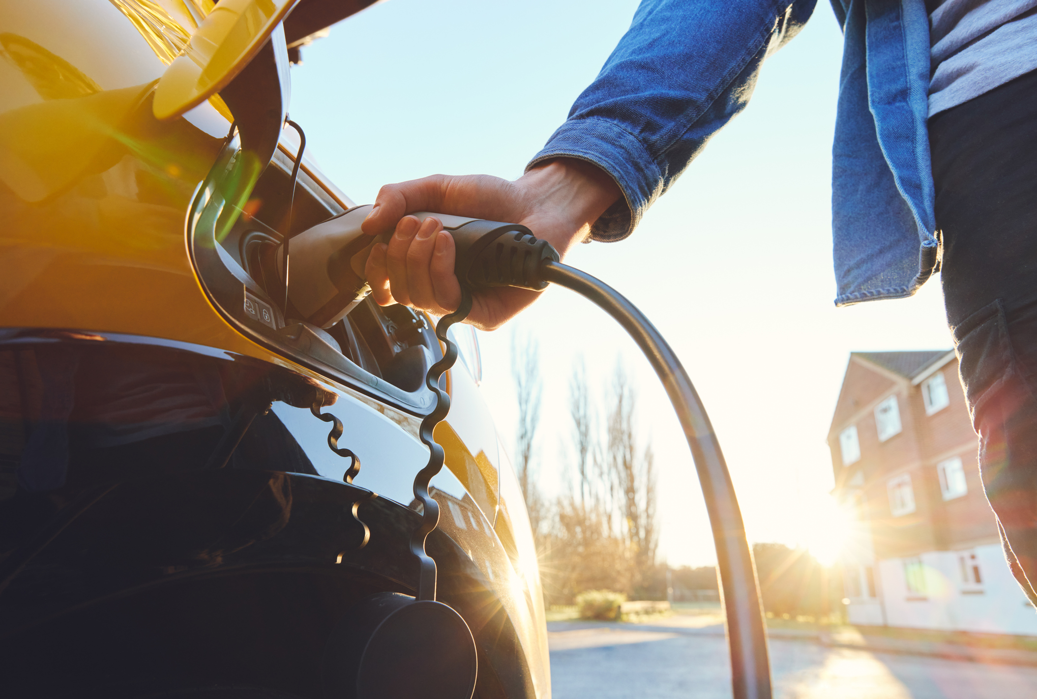 Close-up of person charging yellow electric vehicle.