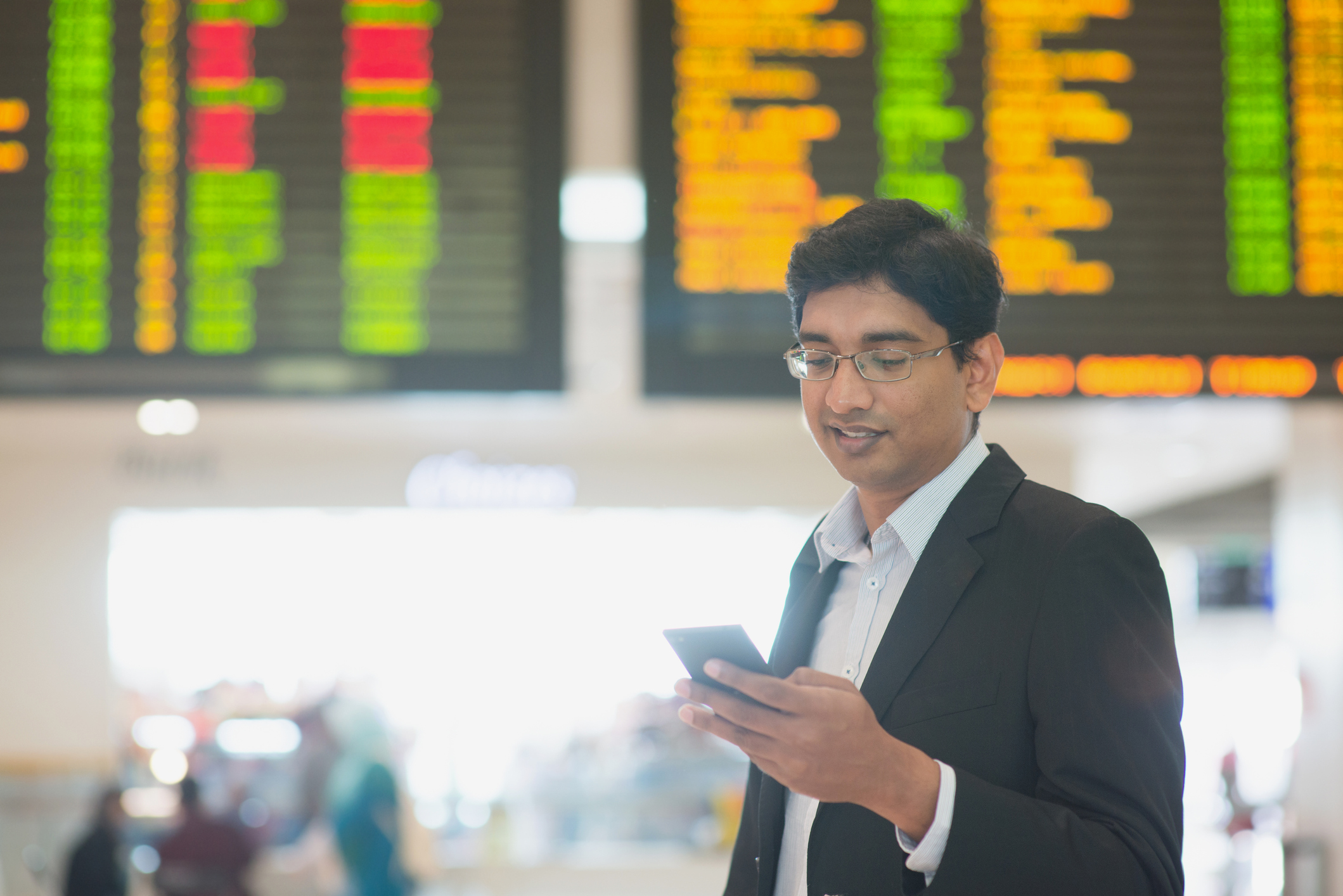A person checks a smartphone in a train station.