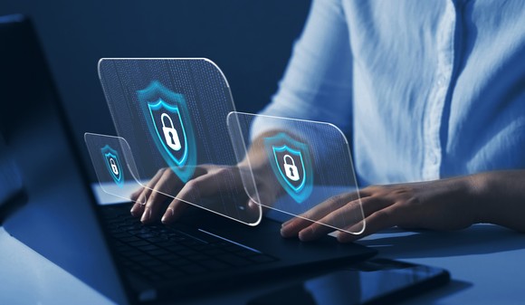 Person typing on laptop with cybersecurity symbols.