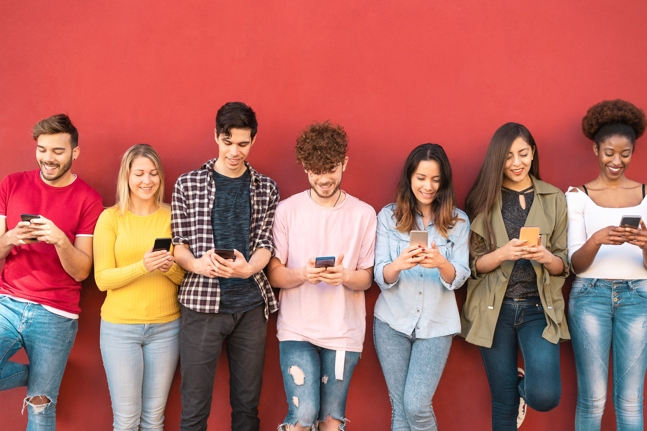 A group of young adults use their smartphones.