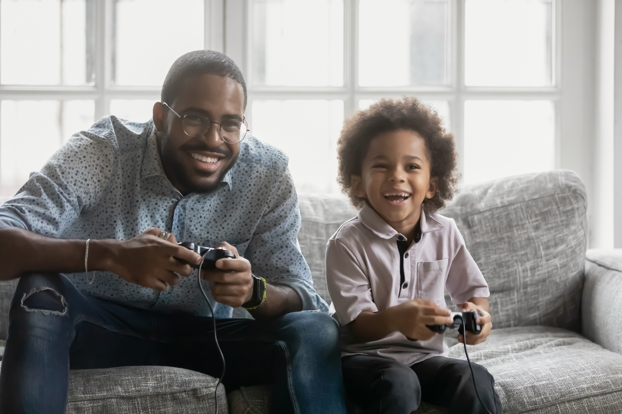 adult and child playing video games on the couch
